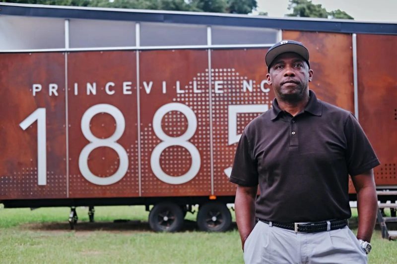 Black man stands in front of 1885 sign.