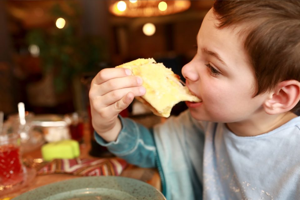 A little boy eating a sandwich at a restaurant.