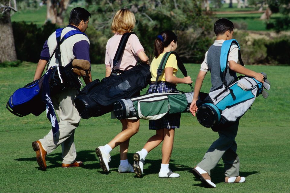 A family of four carrying golf bags.
