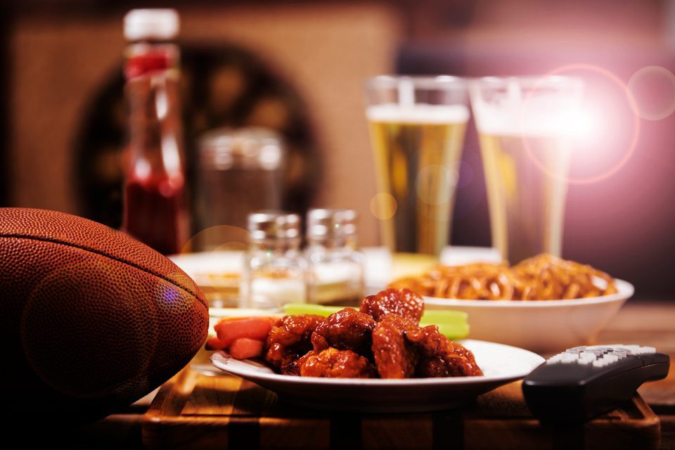 A table with a football, two pints of beer and some bar food.