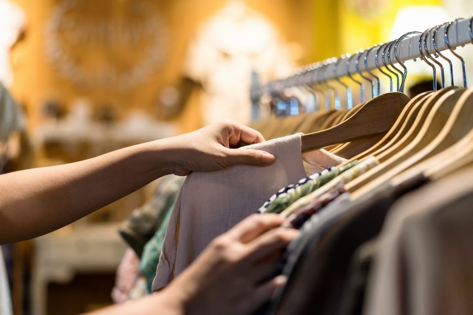  A person sifting through clothes on a rack.