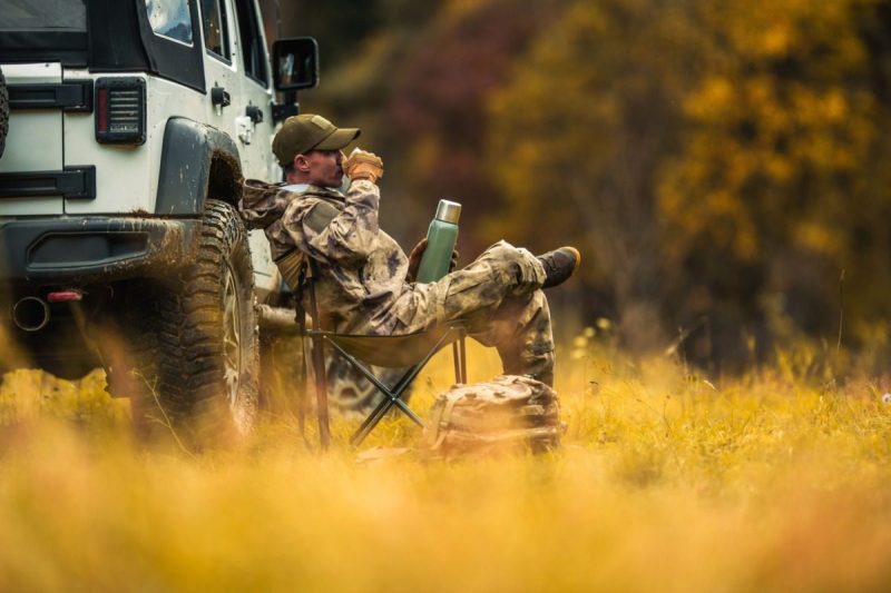 A hunter sits in a chair and rests in a field