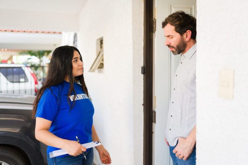 Photo of woman canvasser standing outside a voters' door to chat.